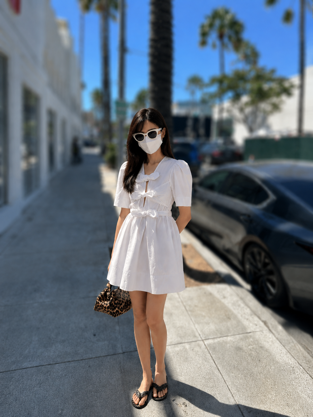 Beverly Hills look: white bow-front mini dress, leopard bag, sandals, white sunglasses